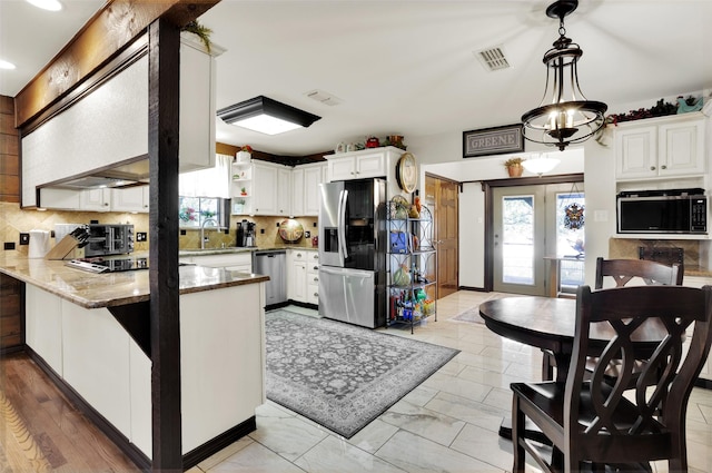 161 Cheyenne Dr, Nocona, TX 76255 - kitchen featuring stainless steel appliances, a peninsula, backsplash, open shelves, and light stone counters