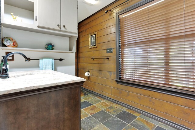 161 Cheyenne Dr, Nocona, TX 76255 - bathroom featuring stone tile floors, wood walls, and vanity