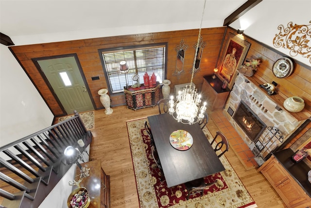 161 Cheyenne Dr, Nocona, TX 76255 - living area with wood walls, light wood-type flooring, a chandelier, stairs, and a stone fireplace