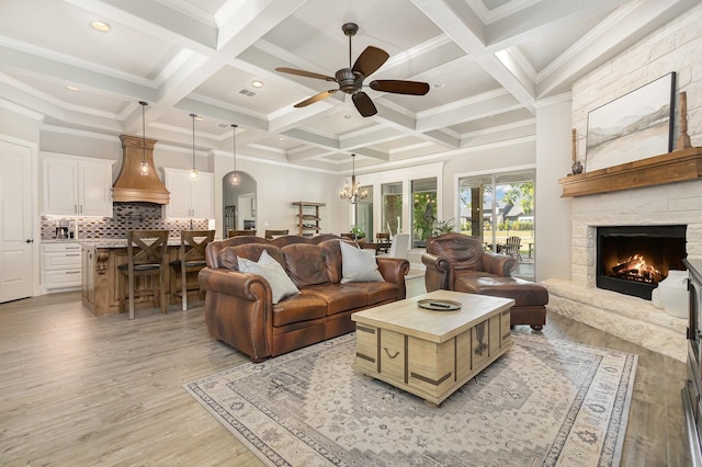3011 Skyhawk Dr, Granbury, TX 76049 - living room featuring a stone fireplace, beam ceiling, ceiling fan, light wood-type flooring, and a chandelier
