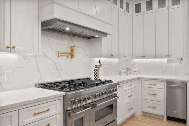 1911 Ozro Rd, Venus, TX 76084 - kitchen with stainless steel appliances, custom exhaust hood, white cabinetry, light stone countertops, and glass insert cabinets