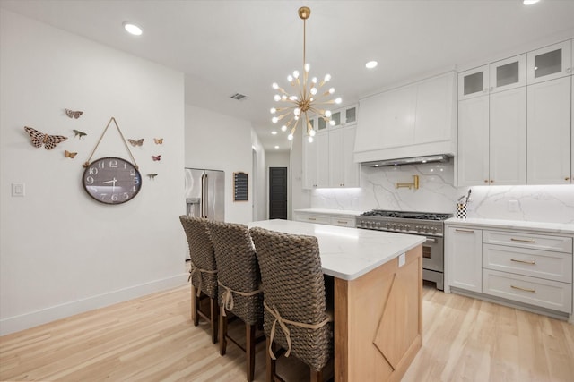 1911 Ozro Rd, Venus, TX 76084 - kitchen with premium appliances, light wood-style flooring, custom exhaust hood, a kitchen island, and tasteful backsplash