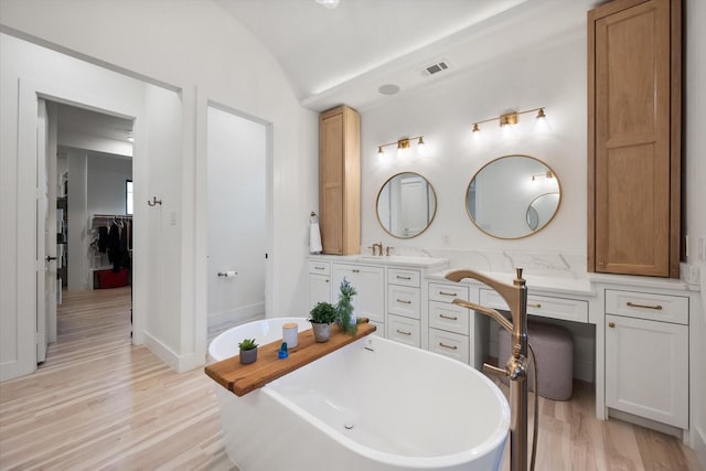 1911 Ozro Rd, Venus, TX 76084 - bathroom with a freestanding tub, wood finished floors, double vanity, vaulted ceiling, and a spacious closet