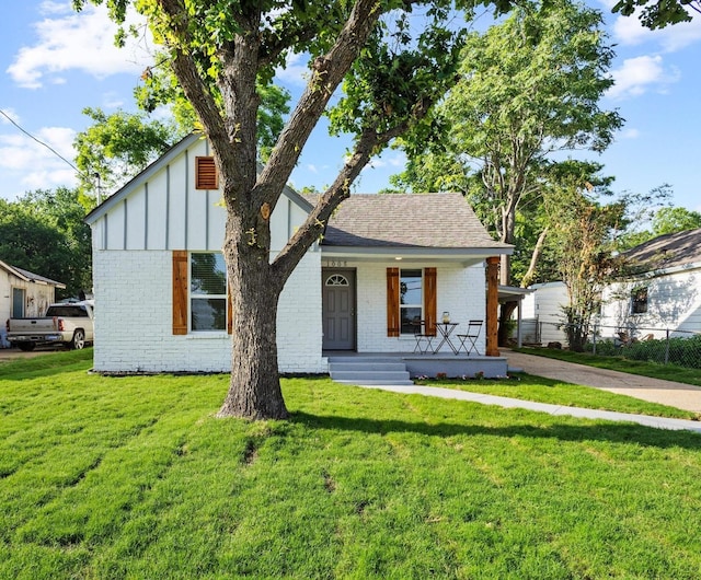 1005 W Bullock St, Denison, TX 75020 - view of front of house with brick siding, covered porch, board and batten siding, and a shingled roof