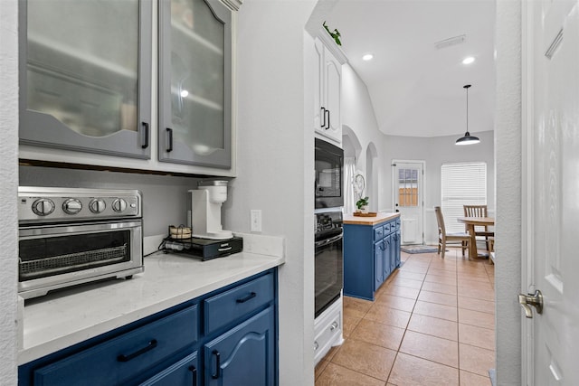 405 High Desert Dr, Fort Worth, TX 76131 - kitchen featuring blue cabinetry, black appliances, arched walkways, light tile patterned floors, and glass insert cabinets