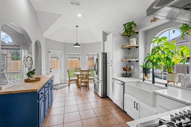 405 High Desert Dr, Fort Worth, TX 76131 - kitchen with wooden counters, blue cabinets, appliances with stainless steel finishes, arched walkways, and open shelves