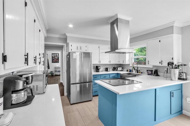 312 Dean St, Athens, TX 75751 - kitchen with freestanding refrigerator, a sink, black electric stovetop, a peninsula, and blue cabinetry