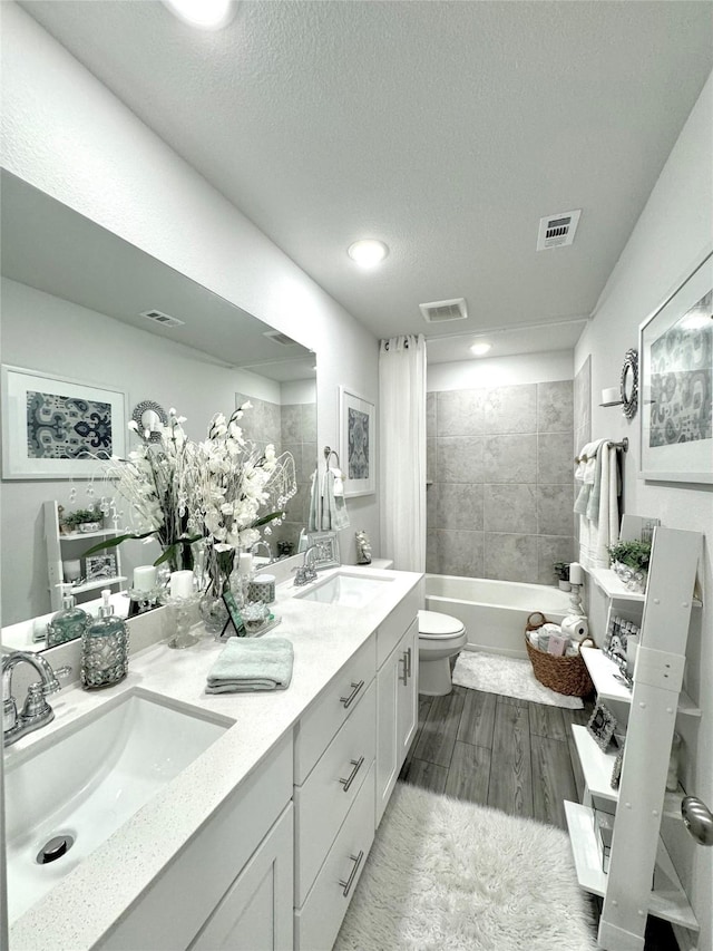 608 N Rain Barrel Pl, Weston, TX 75009 - bathroom featuring toilet, double vanity, a textured ceiling, wood finished floors, and bathing tub / shower combination
