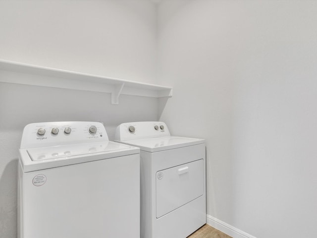 133 Hollytree Ln, Boyd, TX 76023 - laundry room featuring washing machine and clothes dryer, light wood-type flooring, and baseboards