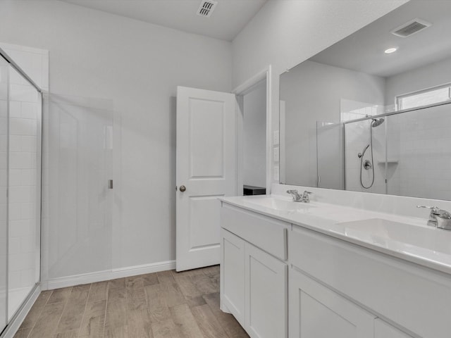 133 Hollytree Ln, Boyd, TX 76023 - bathroom featuring tiled shower, wood finished floors, double vanity, and baseboards