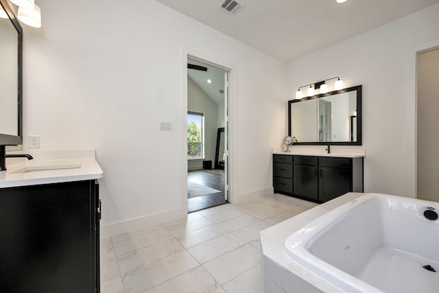 13445 Meadow Cross Dr, Fort Worth, TX 76008 - bathroom featuring two vanities, a bathtub, vaulted ceiling, recessed lighting, and marble look tiles
