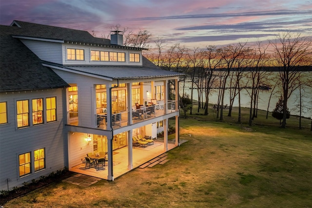 13390 Waterside Dr, Malakoff, TX 75148 - back of property at dusk featuring a patio, a lawn, a chimney, a balcony, and a shingled roof