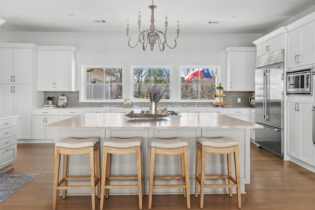 13390 Waterside Dr, Malakoff, TX 75148 - kitchen with built in appliances, tasteful backsplash, a chandelier, and a breakfast bar