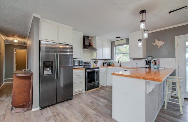 23899 Sagewood Ln, Bedias, TX 77831 - kitchen featuring appliances with stainless steel finishes, wall chimney exhaust hood, a peninsula, white cabinets, and a textured ceiling