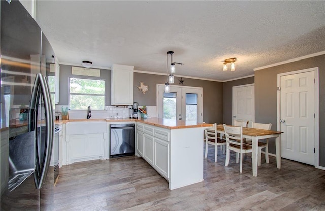 23899 Sagewood Ln, Bedias, TX 77831 - kitchen with freestanding refrigerator, stainless steel dishwasher, a peninsula, light wood-type flooring, and ornamental molding