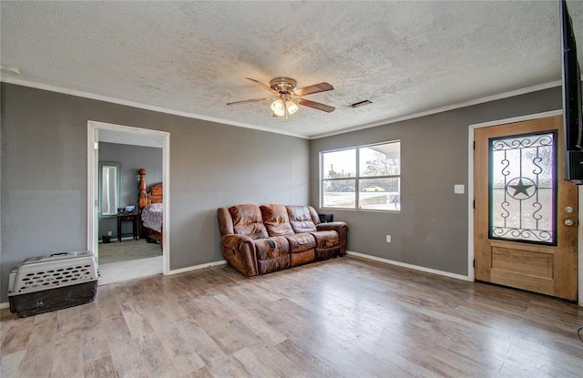 23899 Sagewood Ln, Bedias, TX 77831 - living room featuring a textured ceiling, a ceiling fan, wood finished floors, ornamental molding, and baseboards