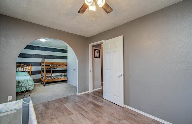 23899 Sagewood Ln, Bedias, TX 77831 - bedroom with wood finished floors, arched walkways, baseboards, and ceiling fan