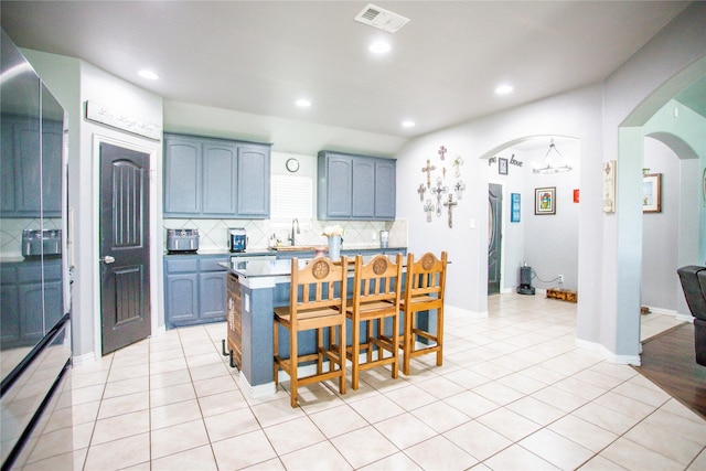 131 Live Oak Ln, Decatur, TX 76234 - kitchen with arched walkways, blue cabinets, decorative backsplash, a kitchen breakfast bar, and recessed lighting