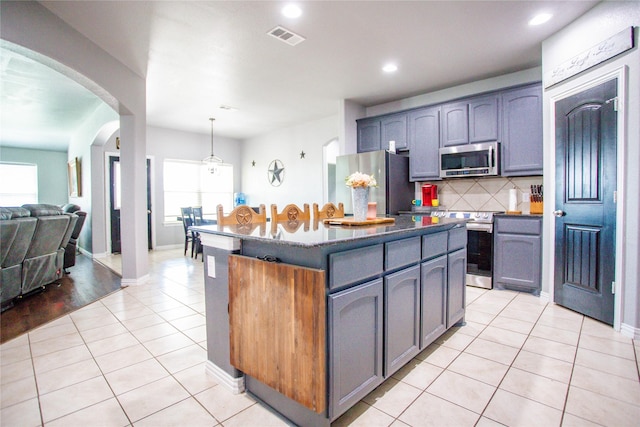 131 Live Oak Ln, Decatur, TX 76234 - kitchen with appliances with stainless steel finishes, light tile patterned flooring, tasteful backsplash, arched walkways, and gray cabinetry