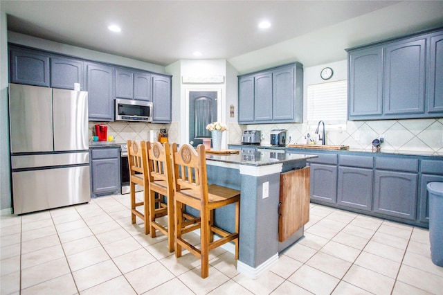 131 Live Oak Ln, Decatur, TX 76234 - kitchen featuring stainless steel appliances, a sink, a kitchen breakfast bar, backsplash, and a kitchen island