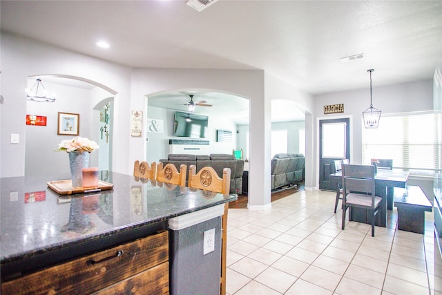 131 Live Oak Ln, Decatur, TX 76234 - kitchen featuring light tile patterned floors, ceiling fan, arched walkways, hanging light fixtures, and dark stone counters