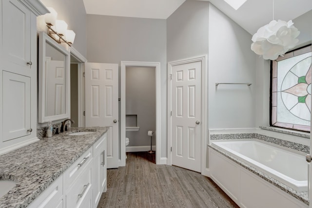 2049 Liverpool Dr, Plano, TX 75025 - full bathroom with wood finished floors, a bath, vanity, toilet, and a skylight