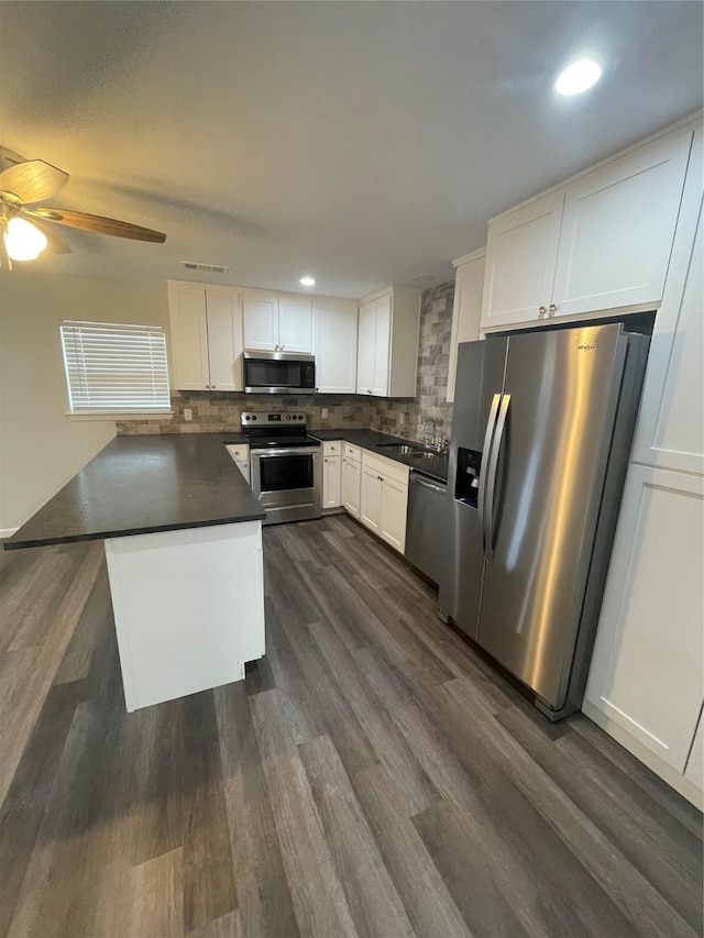 1833 Hood St, Carrollton, TX 75006 - kitchen featuring stainless steel appliances, dark countertops, white cabinets, decorative backsplash, and a ceiling fan