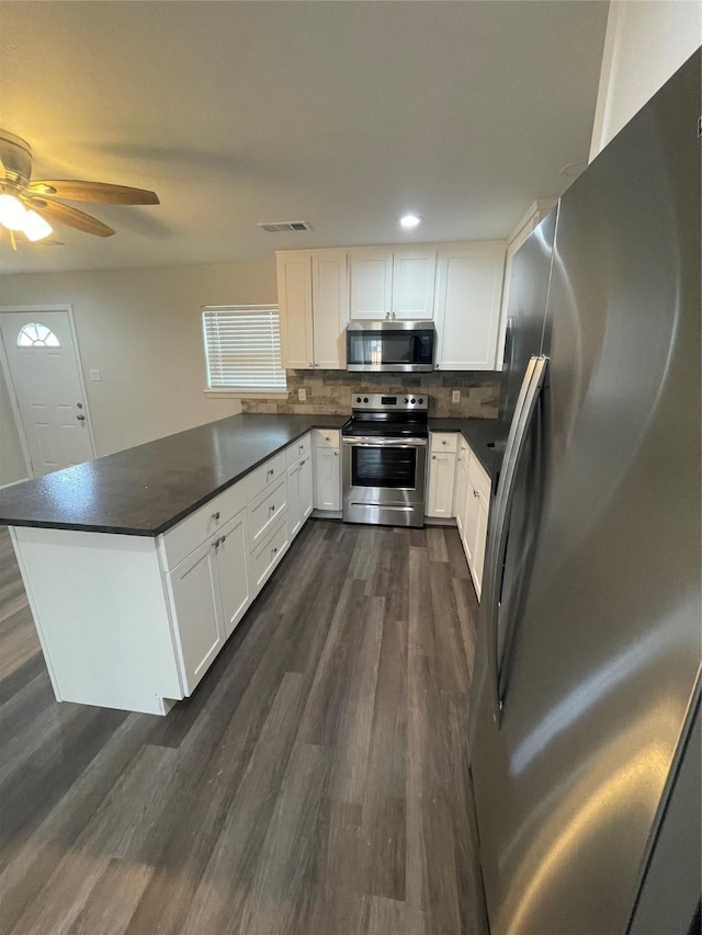 1833 Hood St, Carrollton, TX 75006 - kitchen featuring stainless steel appliances, dark countertops, a peninsula, dark wood-style floors, and white cabinets