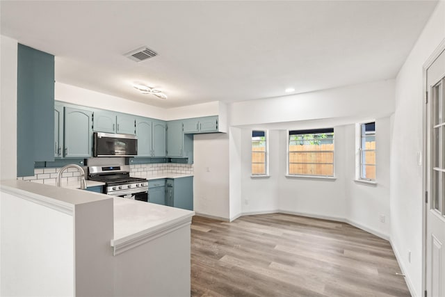 3812 David Ln, Forest Hill, TX 76119 - kitchen with appliances with stainless steel finishes, light countertops, backsplash, light wood-style floors, and a peninsula