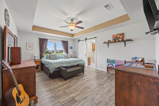 1329 E Highland Rd, Waxahachie, TX 75167 - bedroom featuring a barn door, a raised ceiling, light wood-style flooring, and baseboards
