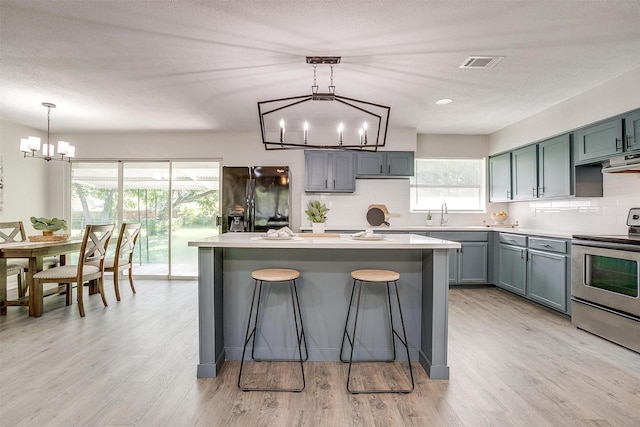1909 Balla Way, Grand Prairie, TX 75051 - kitchen featuring stainless steel electric range oven, a chandelier, black fridge with ice dispenser, decorative backsplash, and a textured ceiling