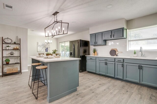 1909 Balla Way, Grand Prairie, TX 75051 - kitchen with black fridge, a sink, a chandelier, light wood-type flooring, and tasteful backsplash