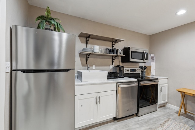 318 S Montreal Ave, Dallas, TX 75208 - kitchen featuring stainless steel appliances, white cabinets, light wood-style floors, light countertops, and open shelves