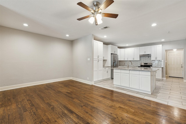 318 S Montreal Ave, Dallas, TX 75208 - kitchen with stainless steel appliances, a sink, white cabinetry, light wood-style floors, and light stone countertops