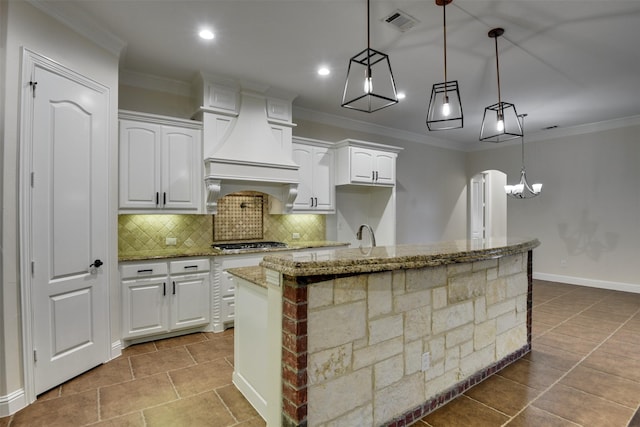 6520 Stone Creek Dr, North Richland Hills, TX 76182 - kitchen with custom range hood, backsplash, white cabinetry, light stone countertops, and crown molding