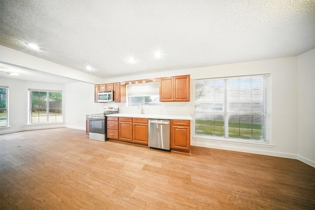 8404 Little Fawn Ln, Dallas, TX 75249 - kitchen with stainless steel appliances, light wood finished floors, baseboards, light countertops, and a textured ceiling