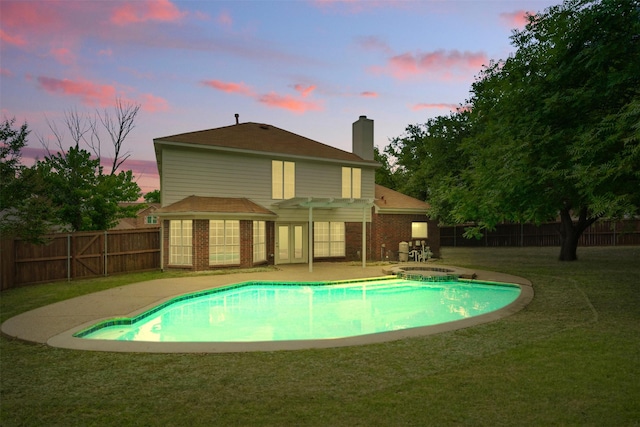 8404 Little Fawn Ln, Dallas, TX 75249 - back of house at dusk with a chimney, brick siding, a patio area, and a pool with connected hot tub