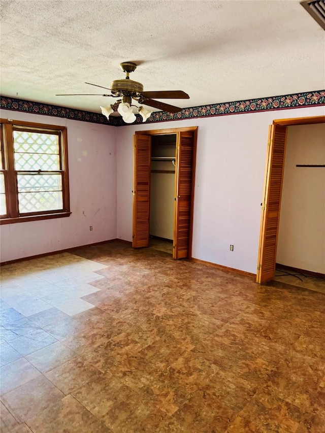 2505 Ormond Pl, Bossier City, LA 71111 - unfurnished bedroom with tile patterned floors, a textured ceiling, ceiling fan, two closets, and baseboards