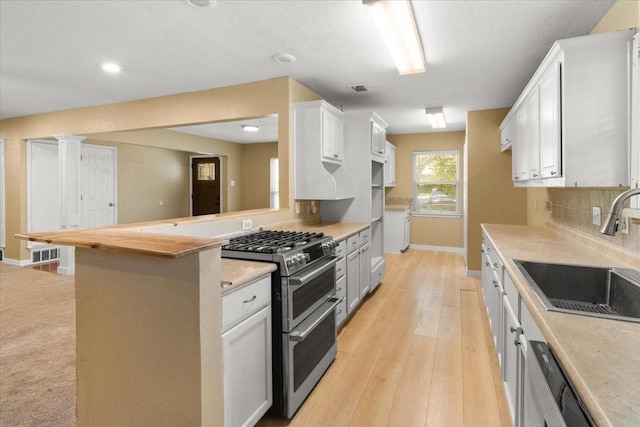 207 Mcmurry Ave, Duncanville, TX 75116 - kitchen featuring range with two ovens, light countertops, white cabinetry, tasteful backsplash, and light wood-style flooring