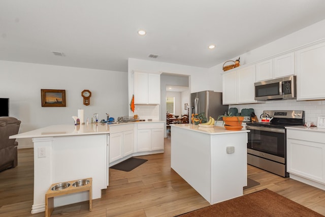 5201 Rockrose Ln, Princeton, TX 75407 - kitchen with appliances with stainless steel finishes, a peninsula, light wood-style floors, decorative backsplash, and white cabinets