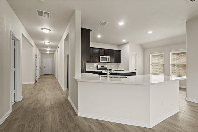 906 Silverbell St, Princeton, TX 75407 - kitchen with stainless steel microwave, light wood-style floors, light countertops, dark brown cabinets, and recessed lighting