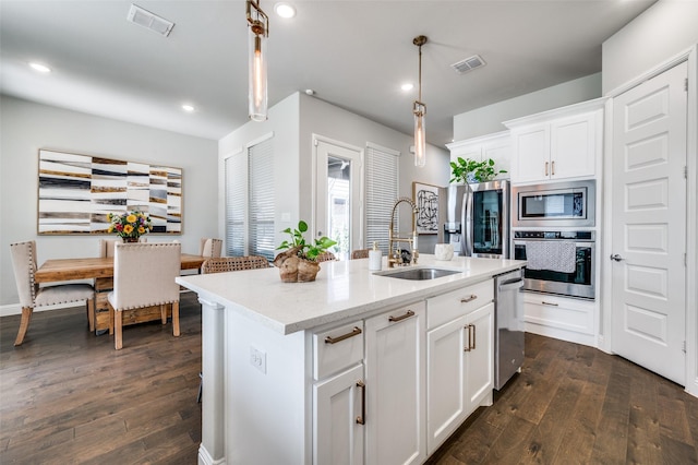 8977 George Cayley Ln, Frisco, TX 75034 - kitchen featuring appliances with stainless steel finishes, a sink, dark wood-type flooring, decorative light fixtures, and white cabinets