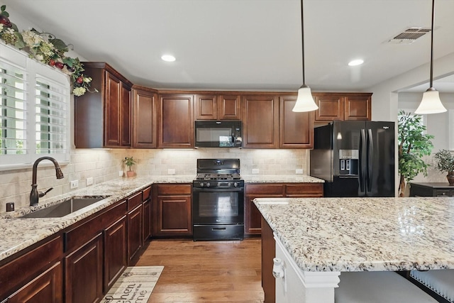 8829 Cantina Bay Ln, Frisco, TX 75036 - kitchen featuring black appliances, a sink, light wood-style flooring, light stone counters, and backsplash