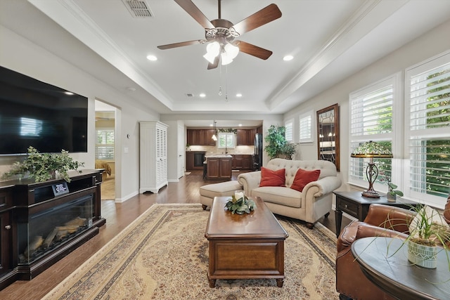 8829 Cantina Bay Ln, Frisco, TX 75036 - living area featuring a tray ceiling, wood finished floors, recessed lighting, ceiling fan, and ornamental molding