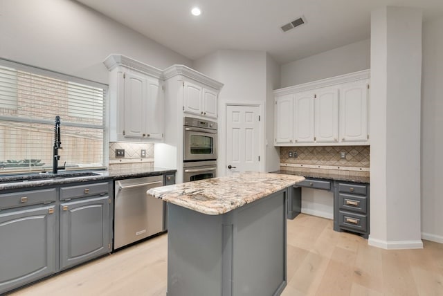 3400 Parr Rd, Grapevine, TX 76051 - kitchen featuring appliances with stainless steel finishes, white cabinetry, tasteful backsplash, light wood-style floors, and a center island