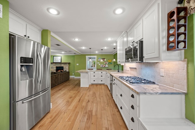 1432 Cimarron Trl, Hurst, TX 76053 - kitchen featuring appliances with stainless steel finishes, a peninsula, white cabinetry, light wood finished floors, and open floor plan