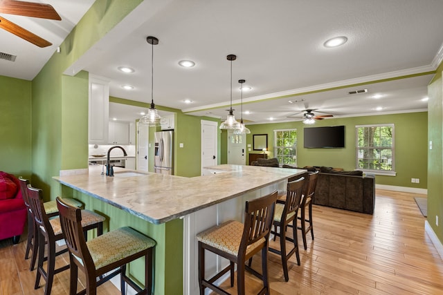 1432 Cimarron Trl, Hurst, TX 76053 - kitchen with a sink, a ceiling fan, stainless steel fridge, ornamental molding, and a kitchen bar