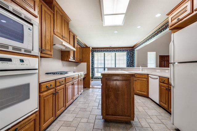 1521 Etain Rd, Irving, TX 75060 - kitchen featuring white appliances, stone tile floors, under cabinet range hood, a skylight, and recessed lighting