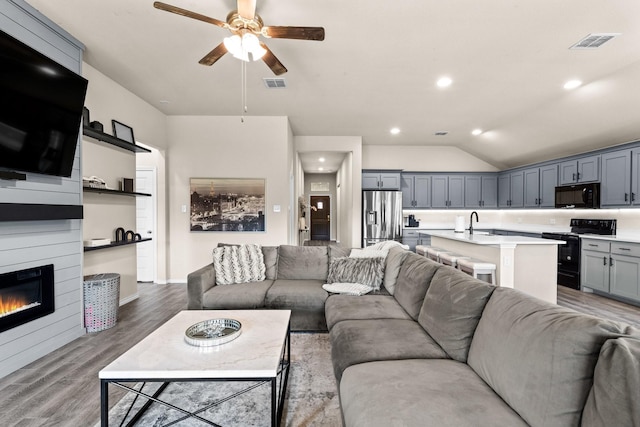 3216 Maroon Creek Rd, Aubrey, TX 76227 - living room with ceiling fan, wood finished floors, vaulted ceiling, a glass covered fireplace, and recessed lighting