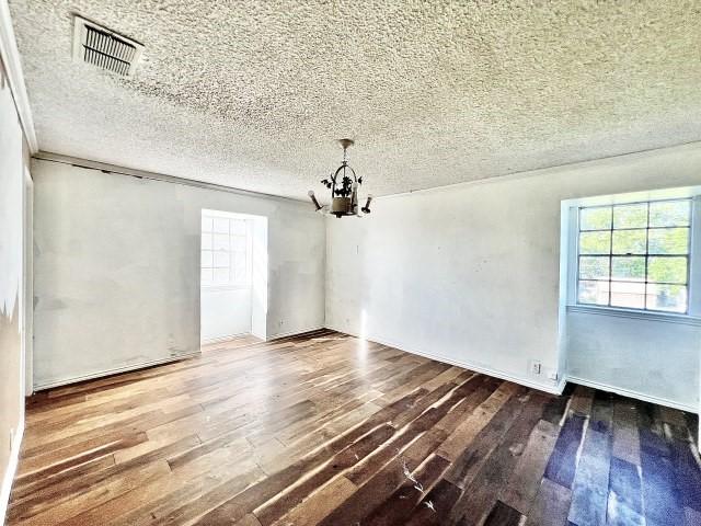 3201 Shoreview Dr, Cleburne, TX 76033 - unfurnished dining area with a chandelier, plenty of natural light, wood-type flooring, and a textured ceiling